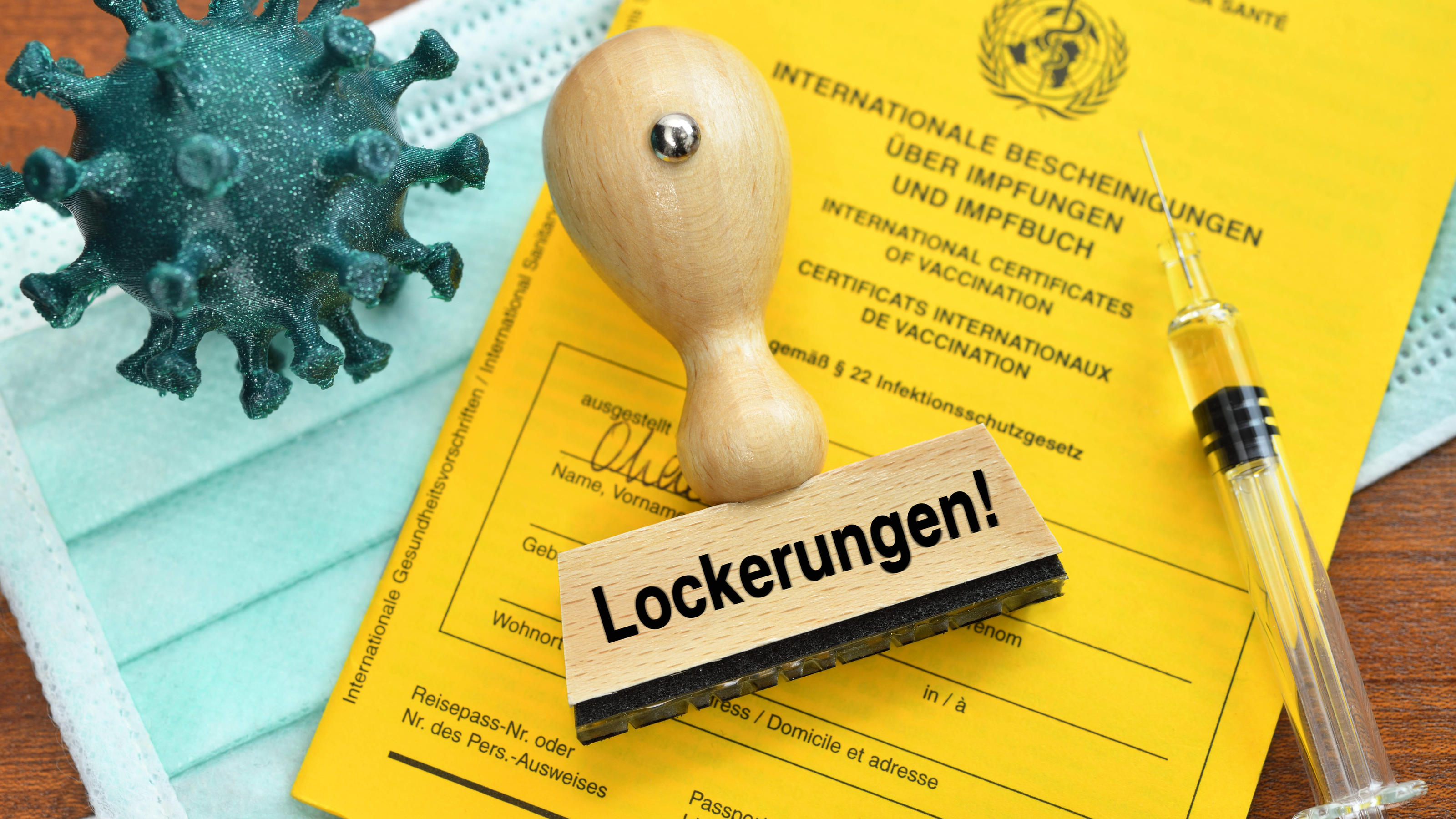 Was tun bei Impfneid in der Beziehung? FOTOMONTAGE, Impfpass, Coronavirus-Modell, Impfspritze und Stempel mit der Aufschrift Lockerungen *** PHOTOMONTAGE, vaccination certificate, coronavirus model, vaccination syringe and stamp with the inscription relaxations