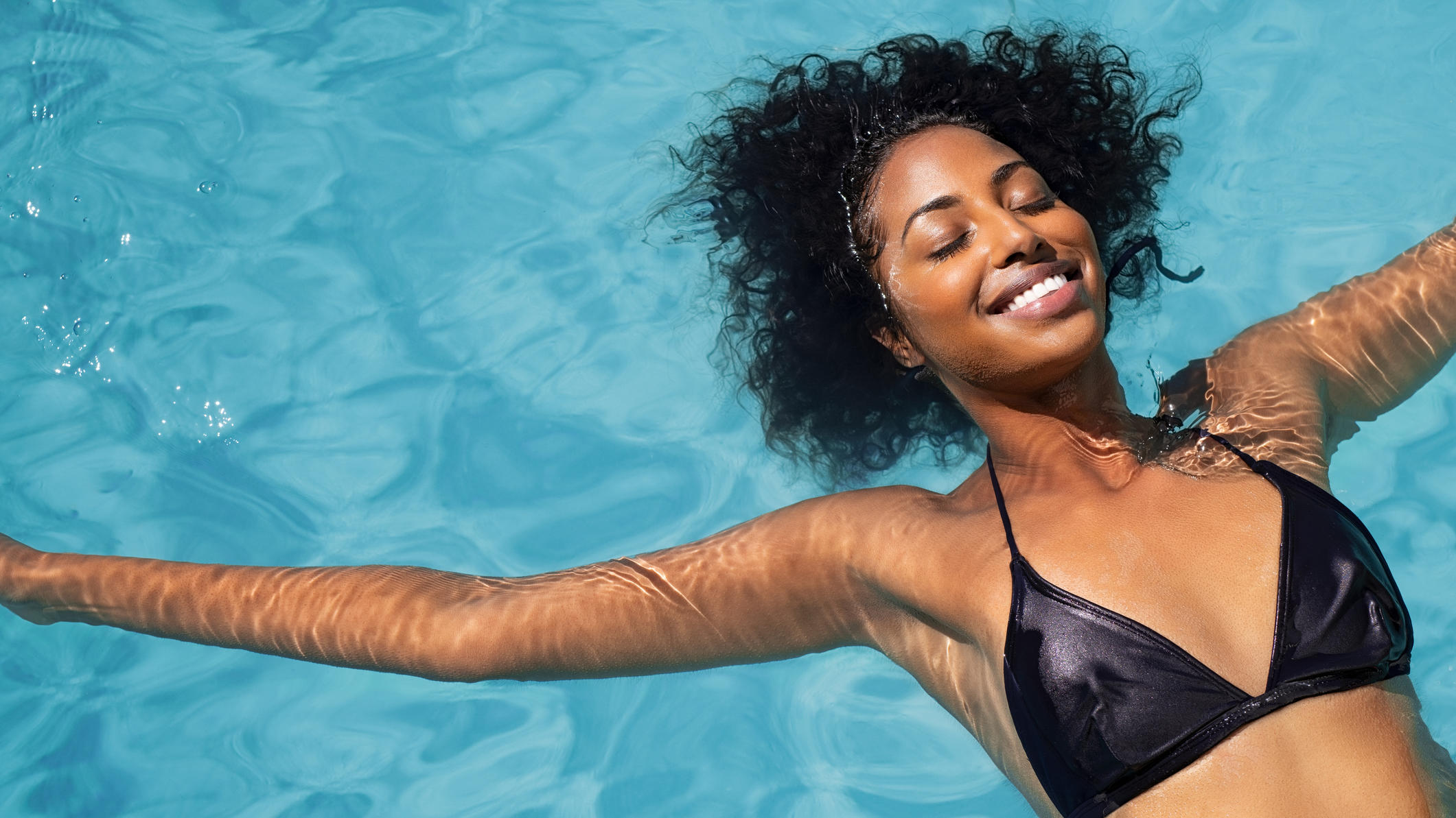 Pool kaufen: Darum ist JETZT der beste Zeitpunkt Pool kaufen: Frau liegt glücklich im Wasser.