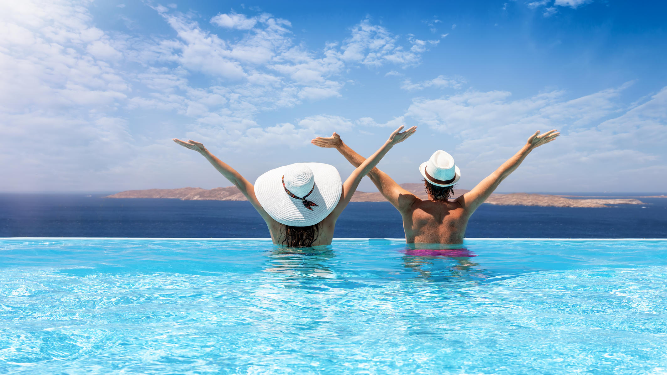 Bundesregierung hebt Reisewarnung für Corona-Risikogebiete auf Paar schwimmt im Pool.