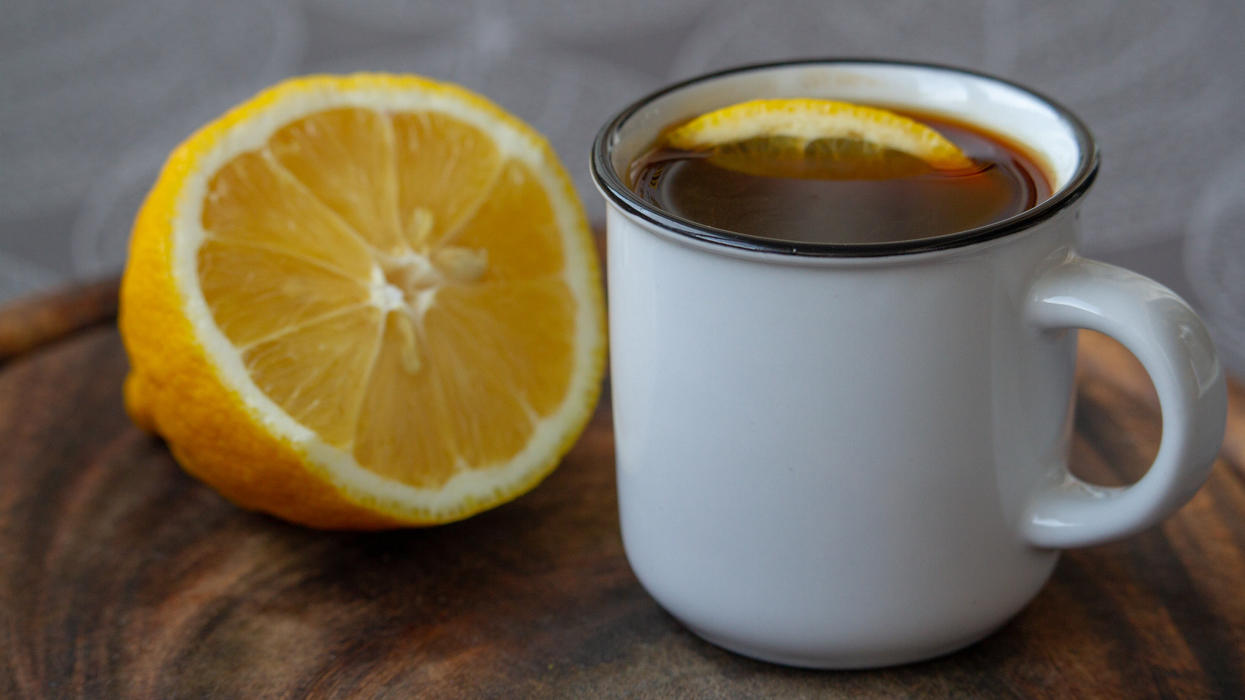 Kaffee mit Zitrone soll die Pfunde purzeln lassen Zitrone liegt neben Kaffeetasse.