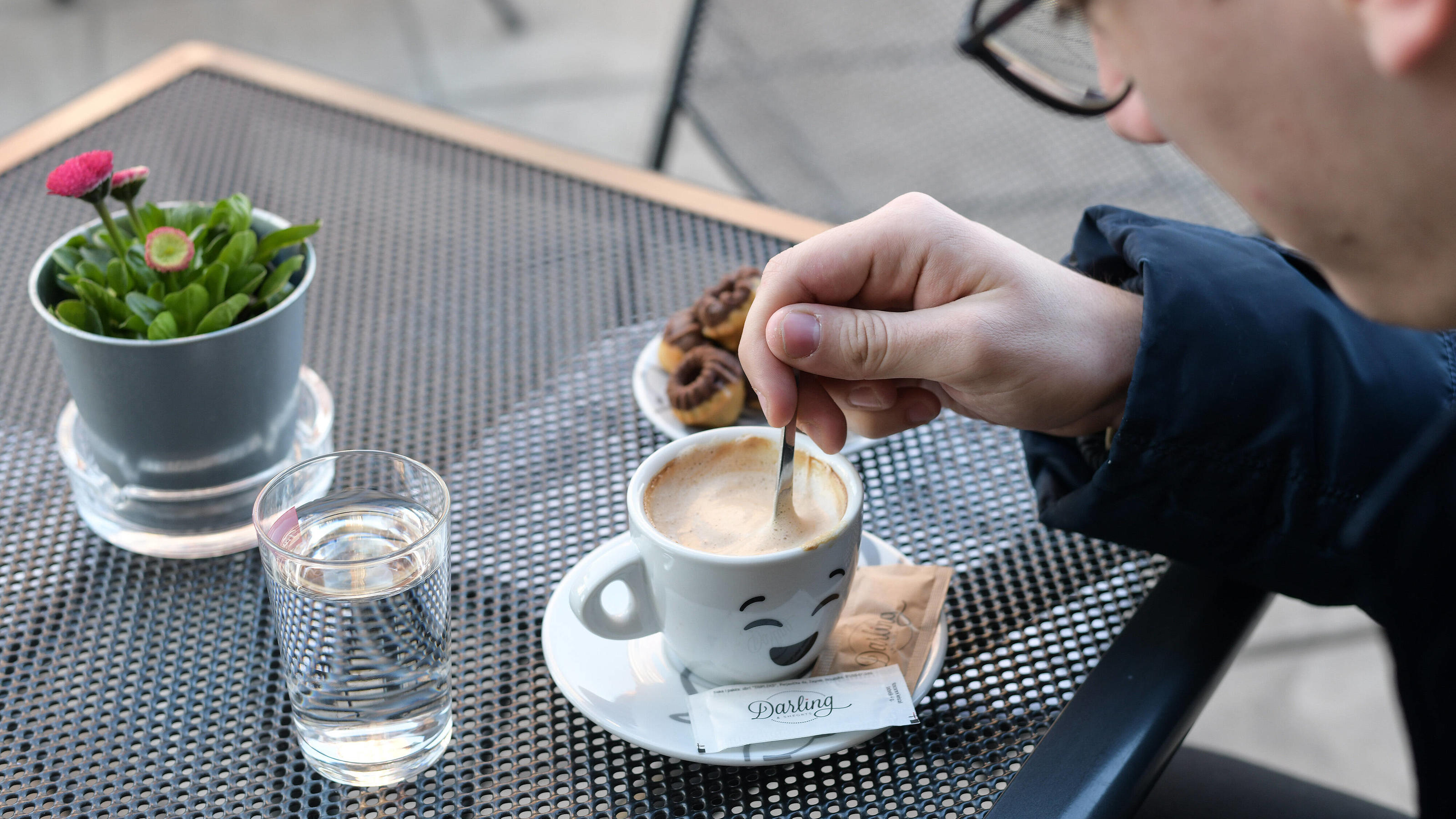 Wann Kaffee gesünder ist als gedacht - und wann er zur Kalorienbombe wird Mann in Café rührt in seinem Kaffee.
