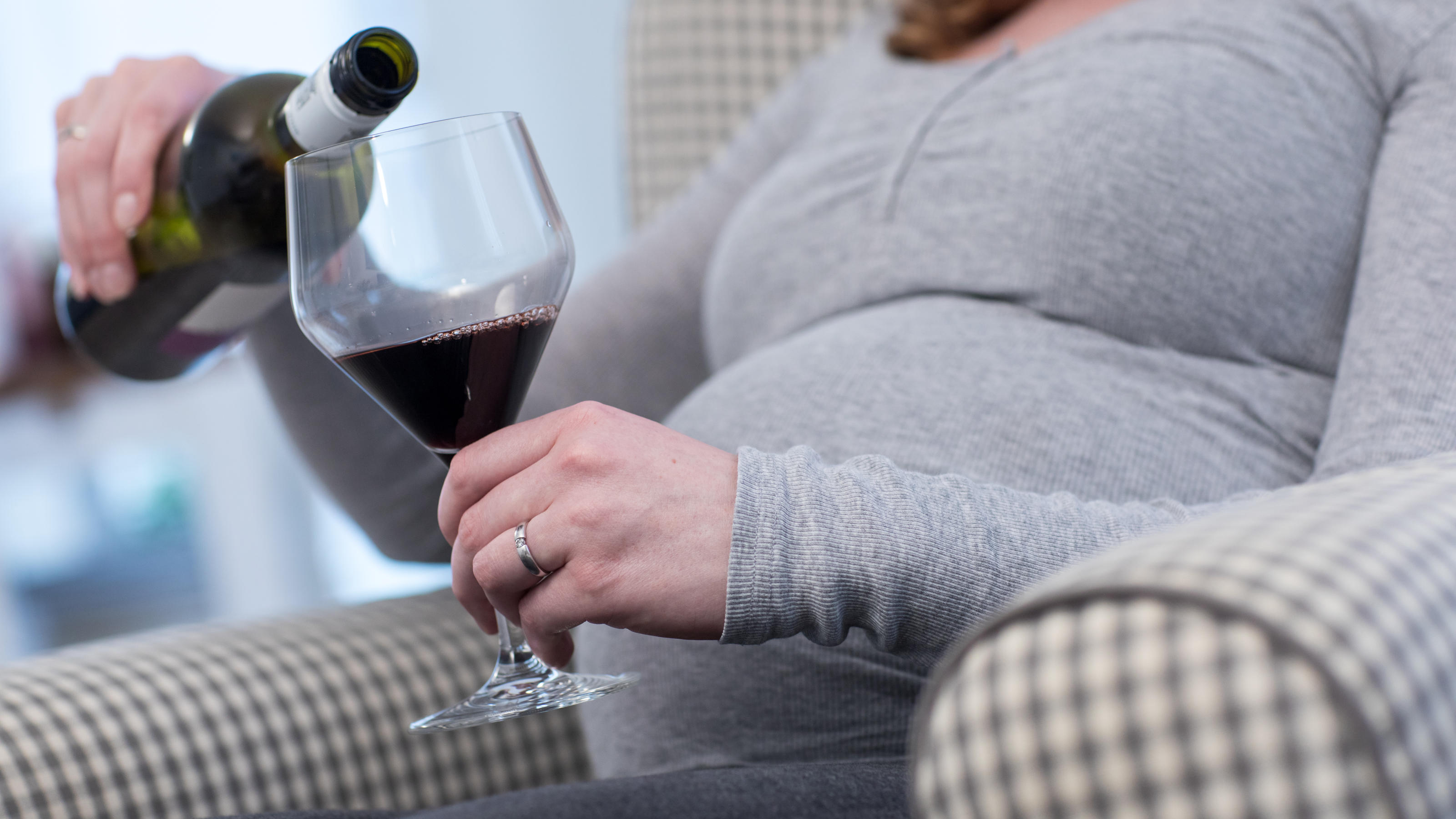 Auch in Bananen enthalten - 10 überraschende Fakten über Alkohol Eine schwangere Frau sitzt am 24.01.2018 in einer Wohnung in Bruchhausen-Vilsen (Niedersachsen) und giesst sich Rotwein in ein Glas (gestellte Szene). Foto: Christin Klose