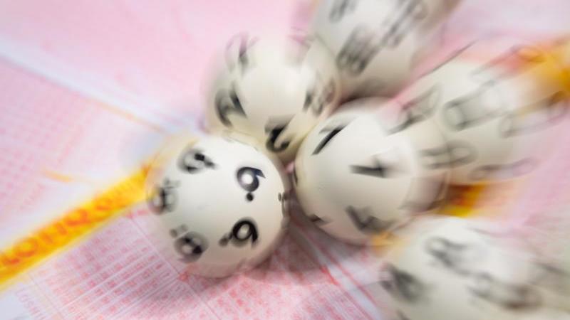 Lottoschein durch Lockdown vergessen: Frau übersieht Millionen-Gewinn! Lotto-Kugeln liegen auf einem Lottoschein.
