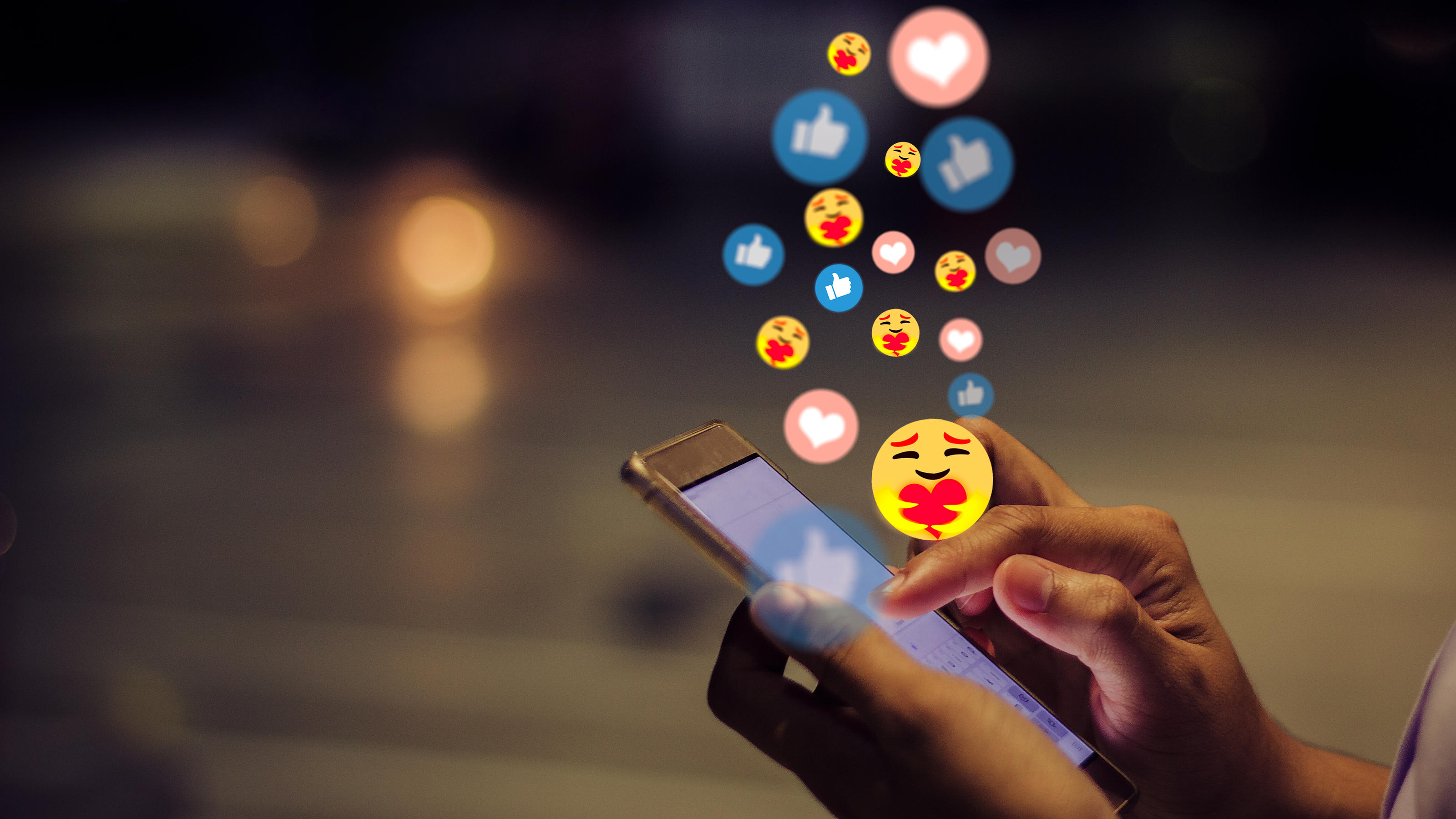 Schwangerer Mann, Disco-Kugel und Troll: Die neuen Emojis sind da! Ein Handy. Darüber schweben verschiedene Emoji-Symbole.