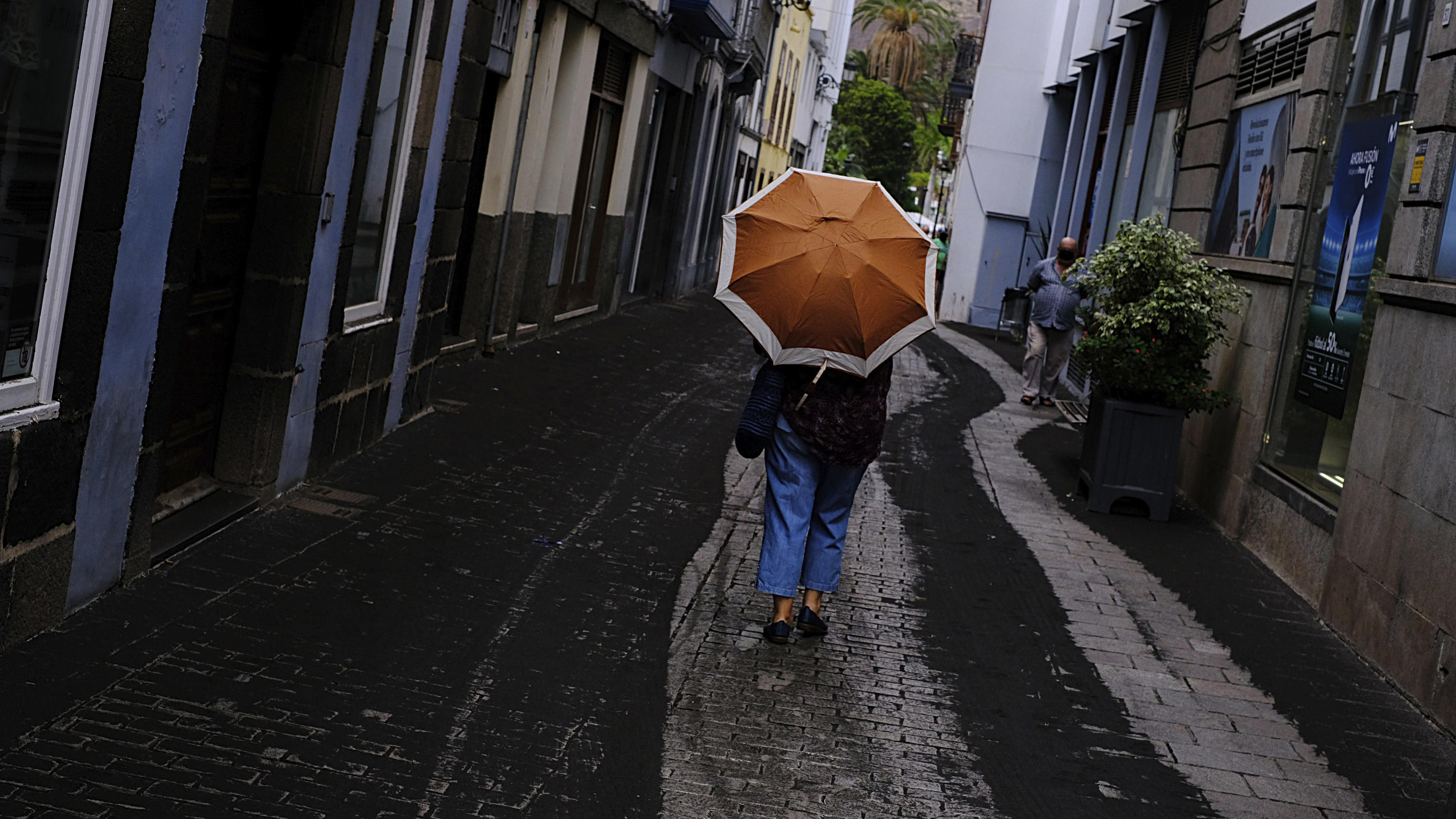 Vulkanausbruch auf La Palma: Der Vulkan Cumbre Vieja auf La Palma ist wieder aufgewacht 27.09.2021, Spanien, Santa Cruz De La Palma: Eine Person geht mit einem Regenschirm durch eine mit Vulkanasche bedeckte Straße in Santa Cruz de la Palma auf der Kanareninsel La Palma. Der Vulkan auf der Kanareninsel La Palma hat am Montag überraschen