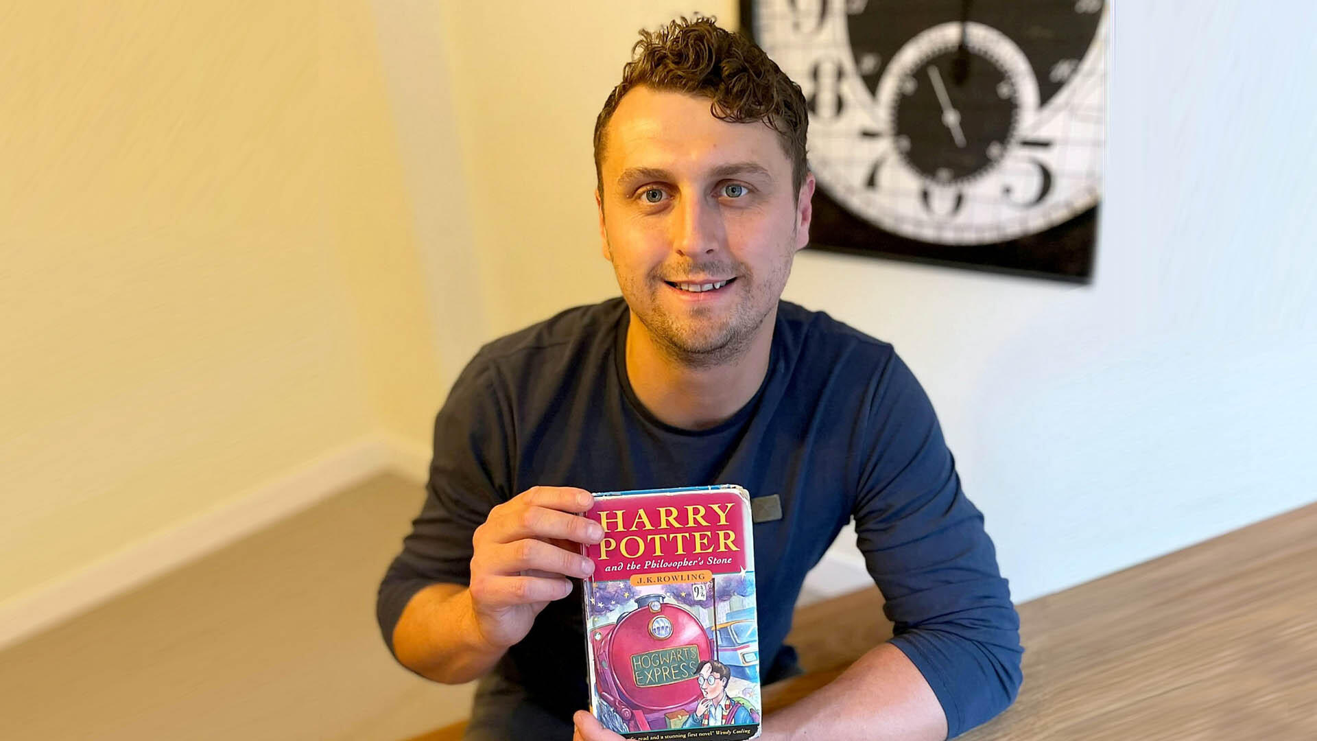 Hier ist der Name Programm! Dieser Harry Potter scheffelt Kohle mit J.K. Rowlings erstem Roman Harry Potter (33) aus Großbitannien sitzt an einem Tisch und hält die Erstauflage in den Händen.