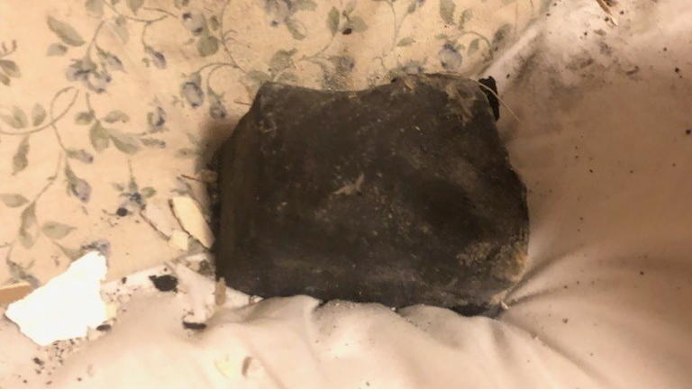 Meteorit landet auf dem Kopfkissen neben schlafender Frau Meteorit, Weltraumbrocken