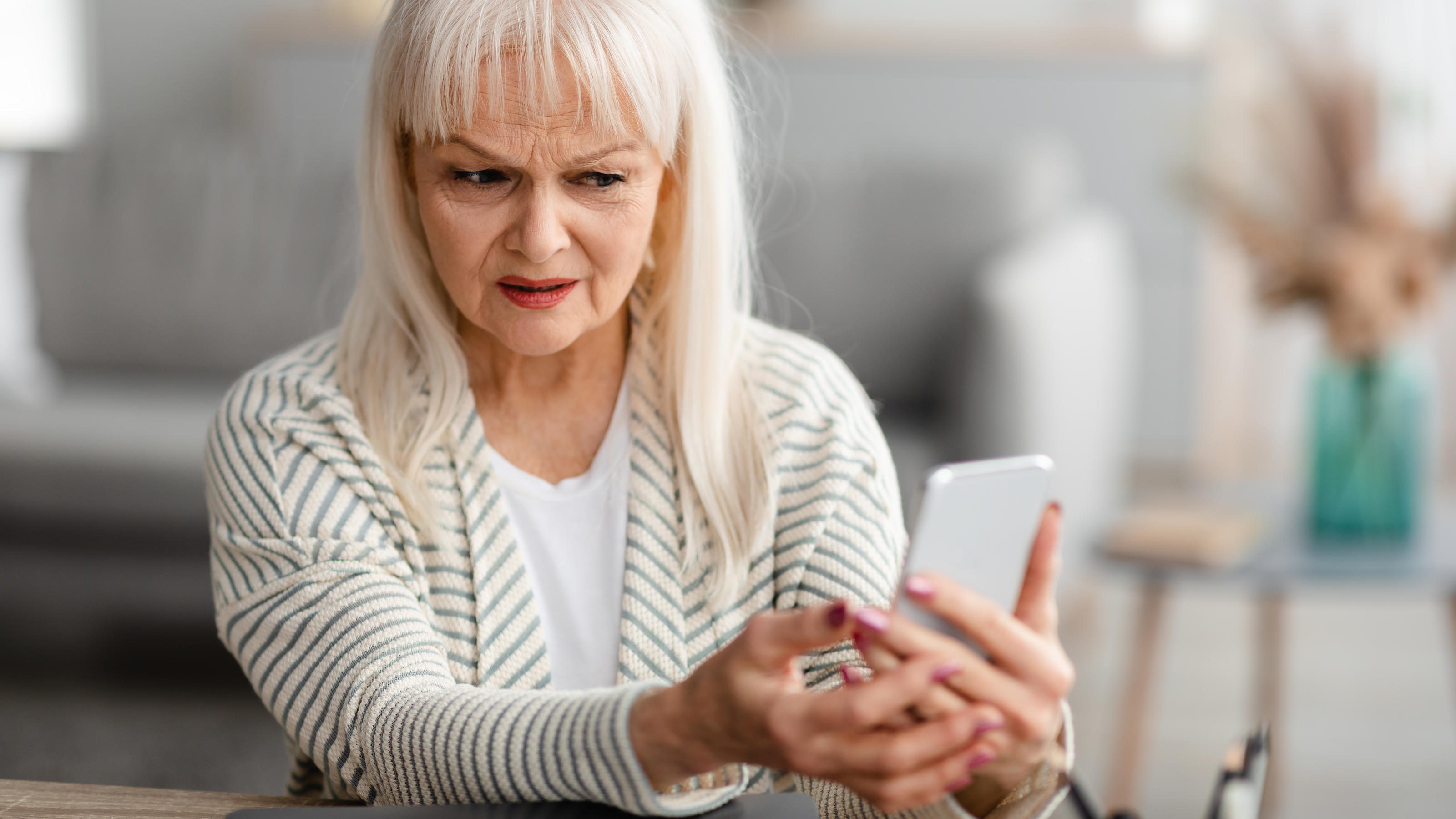 Abzocke per SMS! Verbraucherzentralen warnen vor Smishing-Masche Eine ältere Frau schaut empört und verwirrt auf ihr Smartphone.