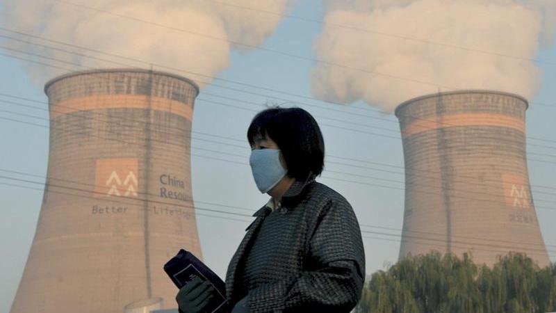 Es tut sich was: Erneuerbare Energien verdrängen Kohle Eine Anwohnerin geht am Kühlturm eines Kohle-Heizkraftwerks in Shenyang im Nordosten Chinas vorbei.