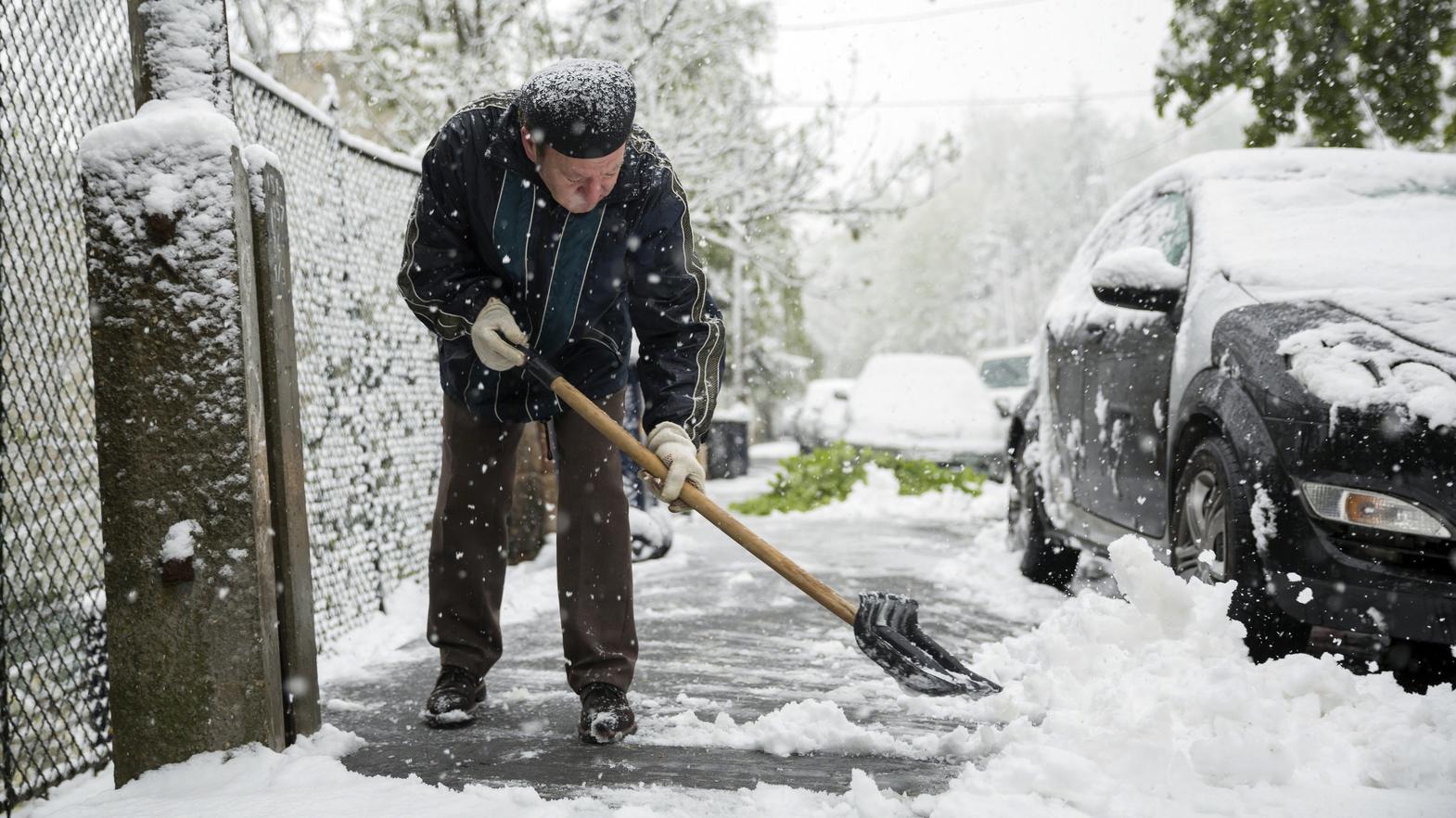 Tief 'Peter' sorgt für Kurz-Winter im April: Viele Gebiete in Europa von starken Schneefällen betroffen Ein Mann schaufelt am 19.04.2017 in Budapest (Ungarn) Schnee vom Bürgersteig