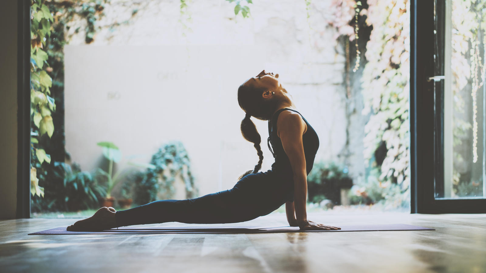 Detox-Yoga: Entgiften Sie Ihren Körper! Eine junge Frau übt auf ihrer Yogamatte die Übung namens Kobra aus, bei der der Oberkörper in die Luft gestreckt wird.
