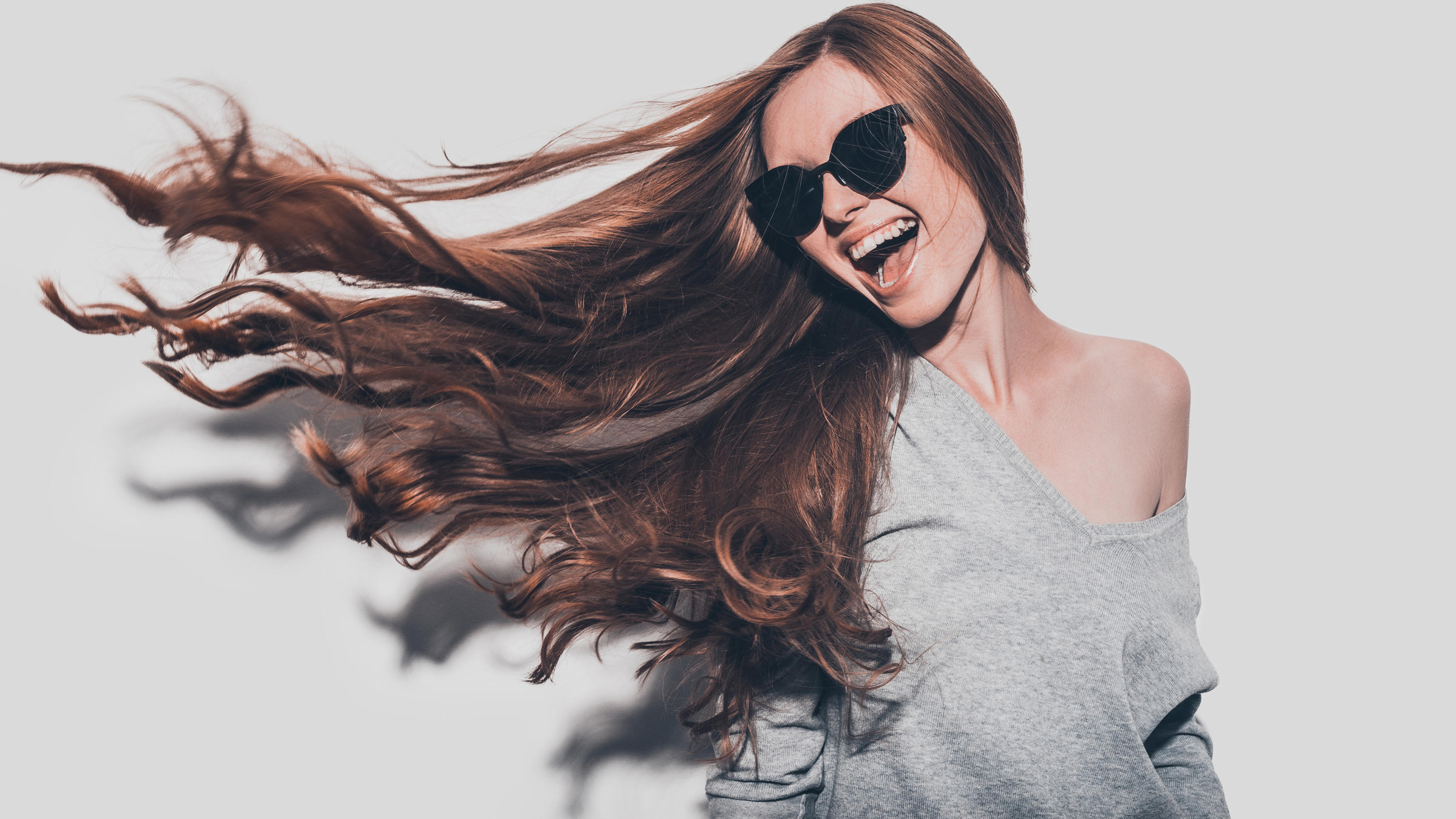 Diese 10 Probleme kennen alle Frauen mit langen Haaren Lachende junge Frau mit sehr langen Haaren und Sonnenbrille