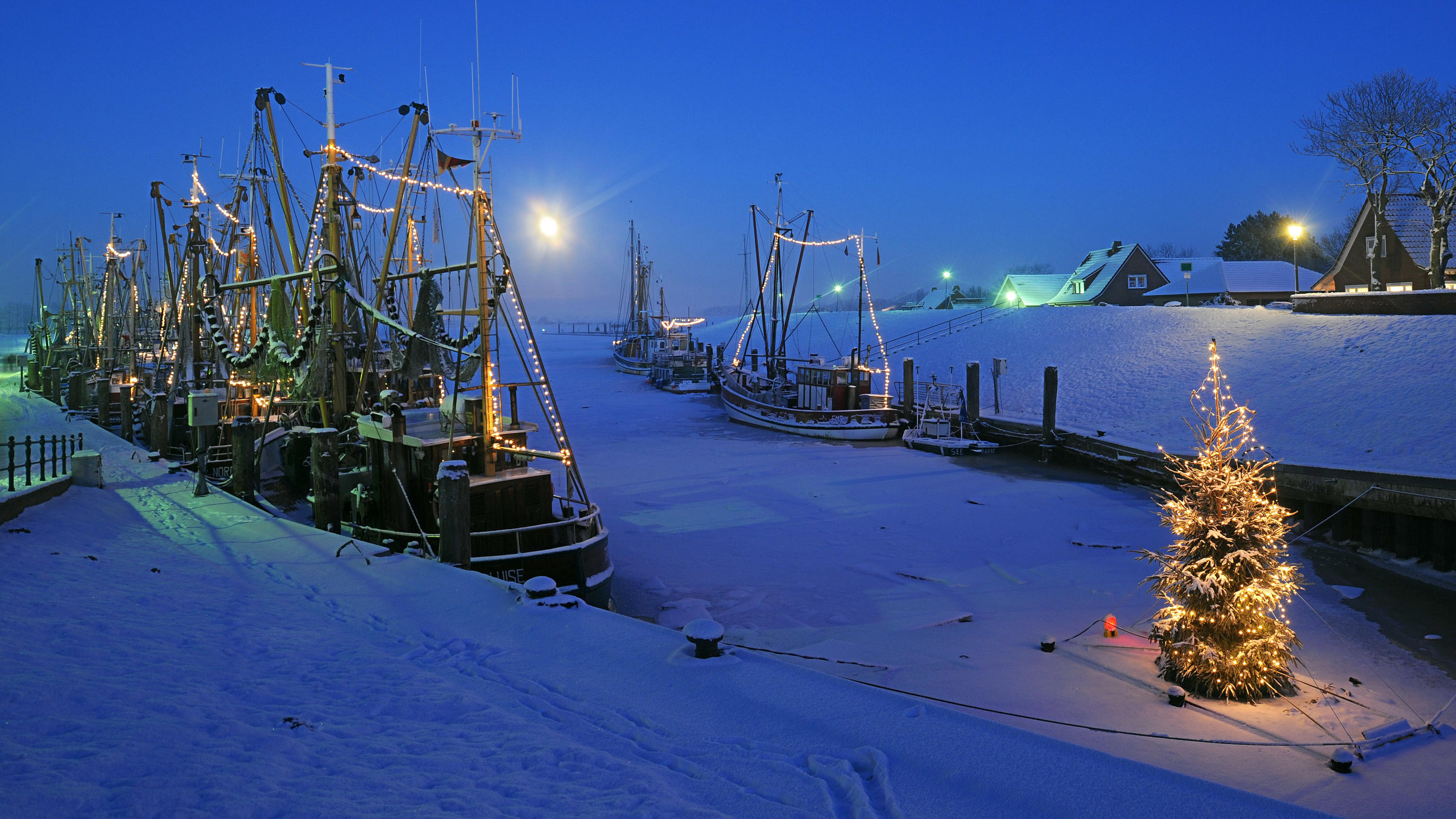 Weiße Weihnachten 2018? So sehen die Chancen in diesem Winter aus ARCHIV - ILLUSTRATION - Ein beleuchteter Weihnachtsbaum steht zur blauen Stunde am 21.12.2010 am zugefrorenen Kutterhafen von Greetsiel (Kreis Aurich). (zu dpa ««I'm Dreaming ...» - Weiße Weihnachten wirklich oft nur ein Traum» vom 15.12.2017) Foto:
