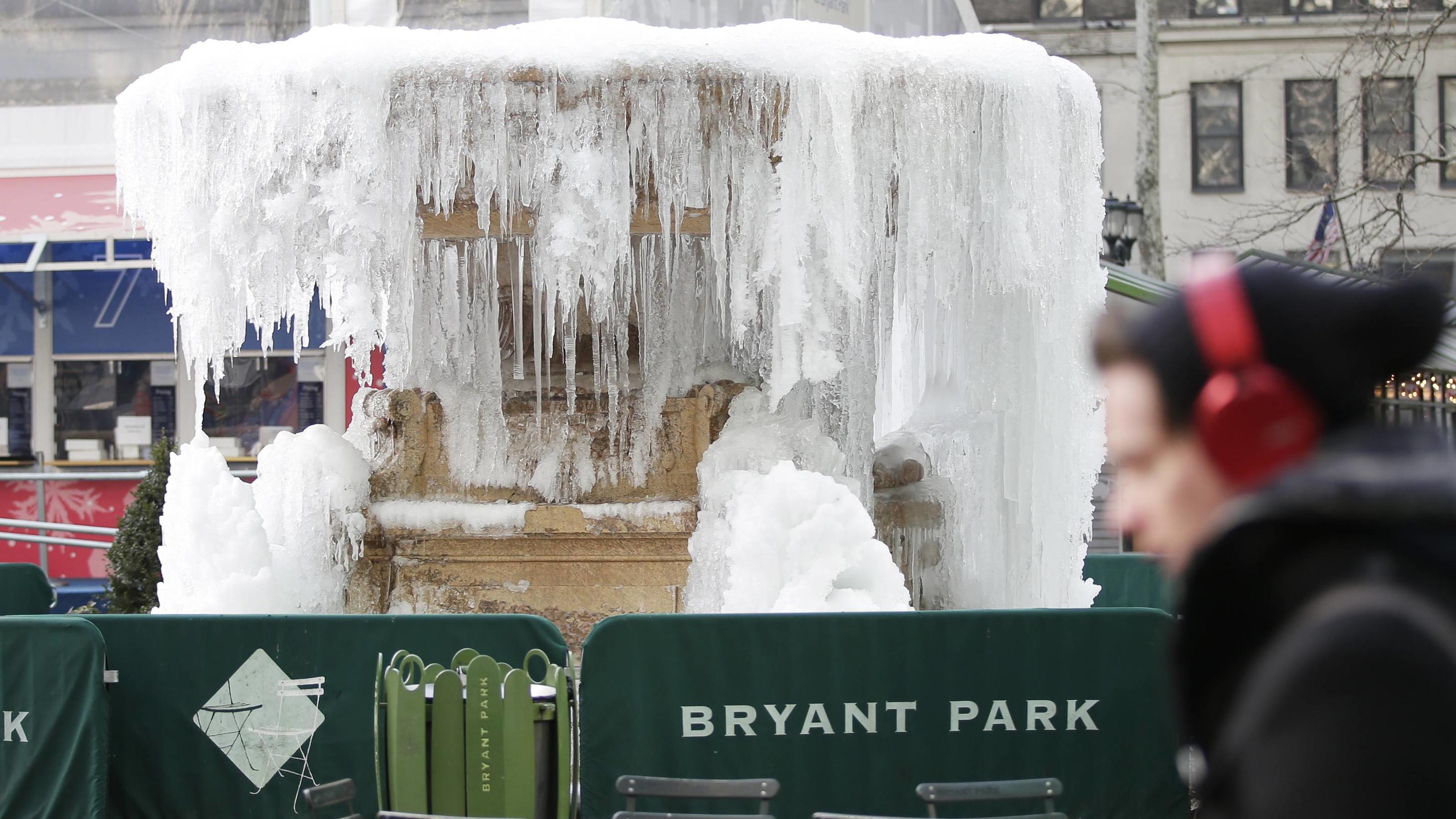 Warum tut sich der Winter im Januar so schwer? Bilder des Tages A pedestrian bundled up for cold weather walks by the frozen fountain in Bryant Park in below freezing temperatures in New York City on January 3, 2018. A massive winter storm called a bomb cyclone is set to batter the Northeast this