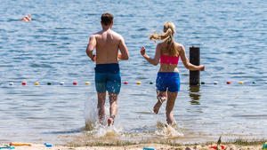 28.05.2018, Niedersachsen, Oldenburg: Eine Frau und ein Mann laufen zum Baden bei sommerlichen Temperaturen und Sonnenschein in den Woldsee. Foto: Mohssen Assanimoghaddam/dpa +++ dpa-Bildfunk +++