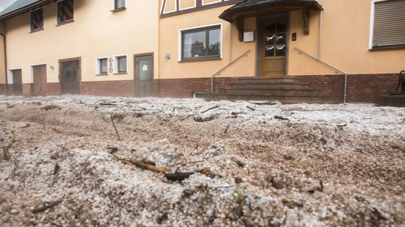 27.05.2018, Hessen, Hetzerode: Hagelkörner und Schlamm liegen auf einer Straße. Feuerwehren und Rettungskräfte sind in der Region im Einsatz und pumpen überflutete Keller leer und räumen Schlammlawinen. Foto: Bernd März/dpa-Zentralbild/dpa +++ dpa-Bi