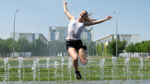 31.05.2018, Berlin: Johanna aus Frankfurt am Main springt über die Wasserfontänen vor dem Bundeskanzleramt. Foto: Paul Zinken/dpa +++ dpa-Bildfunk +++