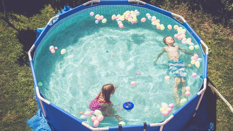 Boy and girl in swimming pool surrounded by balloons model released Symbolfoto PUBLICATIONxINxGERxSUIxAUTxHUNxONLY SARF002067  