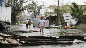 15.09.2018, Philippinen, Tuguegarao City: Anwohner gehen über eine verwüstete Straße, nachdem der Taifun «Mangkhut» wütete. Taifun «Mangkhut» ist im Norden der philippinischen Hauptinsel Luzon mit Wucht auf Land getroffen. Der Taifun entfaltete Windgeschwindigkeiten von bis zu 205 Kilometern pro Stunde. Foto: Aaron Favila/AP/dpa +++ dpa-Bildfunk +++