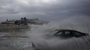 27.09.2018, Griechenland, Rafina: Ein Auto wird beim Fahren über eine Straße im Hafen von einer Welle getroffen. Den zweiten Tag in Folge haben stürmische Winde erhebliche Probleme im Fährverkehr in der Ägäis und im Ionischen Meer verursacht. Foto: Thanassis Stavrakis/AP/dpa +++ dpa-Bildfunk +++