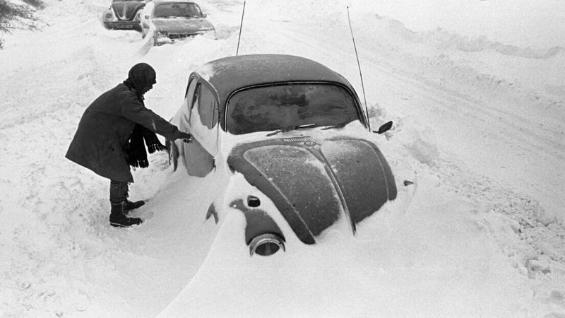 ARCHIV - 31.12.1978, Schleswig-Holstein, Cuxhaven: Ein Autofahrer steht neben seinem am Straßenrand im Schnee stecken gebliebenen VW-Käfer, aufgenommen bei Cuxhaven am 31.12.1978. Der Temperatursturz vom 29. Dezember 1978 führte in Norddeutschland, d