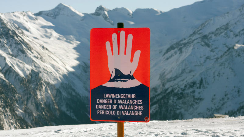 Symbolbild: Ein Schild warnt im Skigebiet auf dem Wildkogel bei Neukirchen im Bundesland Salzburg in den Alpen in Österreich vor Lawinengefahr. Im Hintergrund das Massiv des Großvenedigers. (zu dpa "Sechs Schüler aus Deutschlan