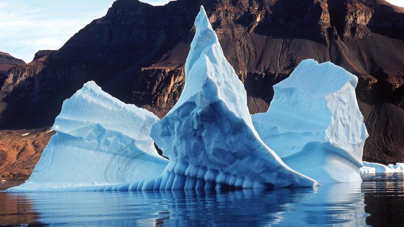 Ein bizarr geformter Eisberg spiegelt sich im Scoresby Sund im Wasser des Atlantischen Ozeans (Archivfoto von 2001). Die Pole sind wichtig für das Leben auf der ganzen Welt. 