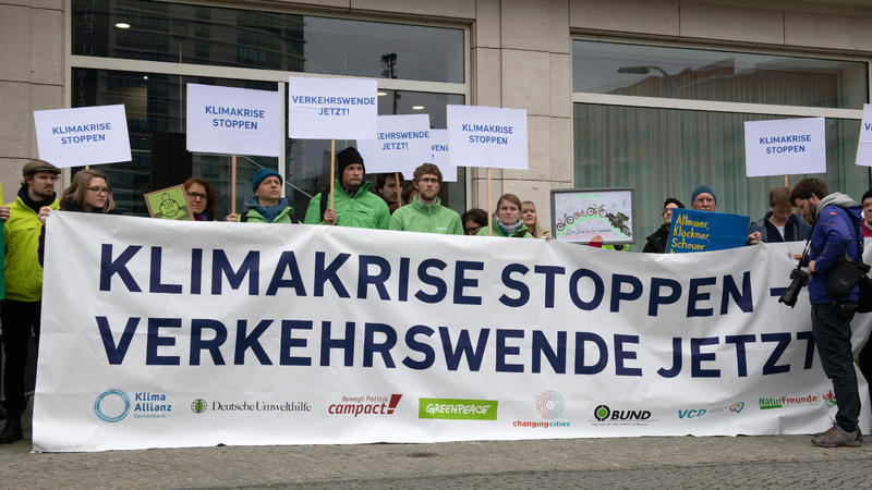 21.03.2019, Berlin: Demonstranten stehen mit Schildern und einem Transparent vor dem Bildungswerk der Wirtschaft. Dort protestierten Mitglieder verschiedener Umweltschutz-Organisationen unter dem Motto "Klimakrise stoppen - Verkehrswende jetzt". Anla