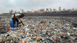 ARCHIV - 04.06.2018, Indien, Mumbai: Ein Mann sammelt Plastik und andere wiederverwertbare Materialen an der von Plastiktüten und sonstigen Müll übersäten Küste des Arabisches Meeres. (zu dpa "Bundesregierung will Exportverbot für unsortierten Plastikmüll") Foto: Rafiq Maqbool/AP/dpa +++ dpa-Bildfunk +++