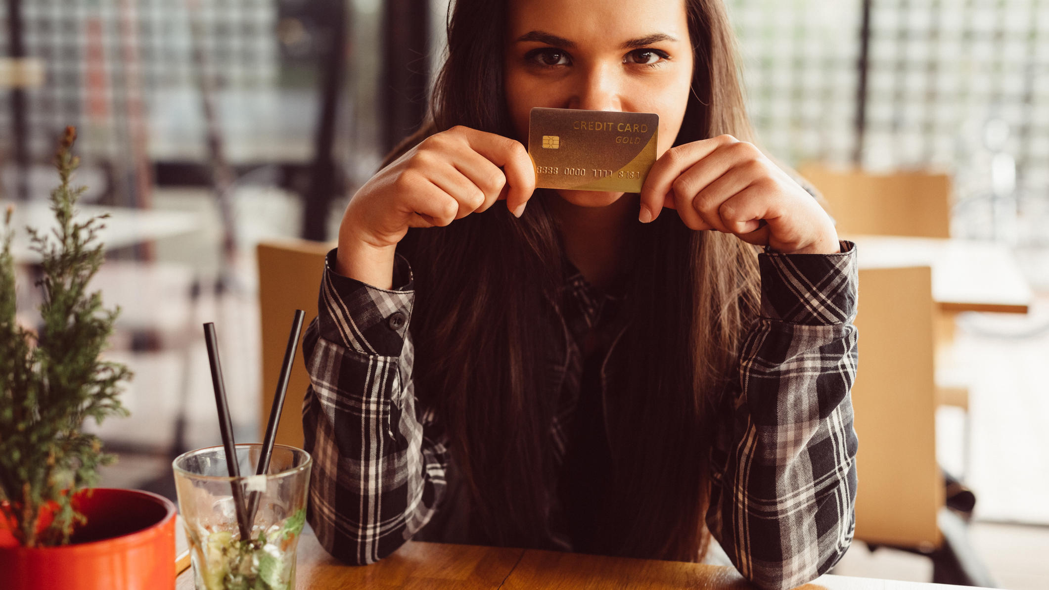 Mädchen hält Kreditkarte vor den Mund