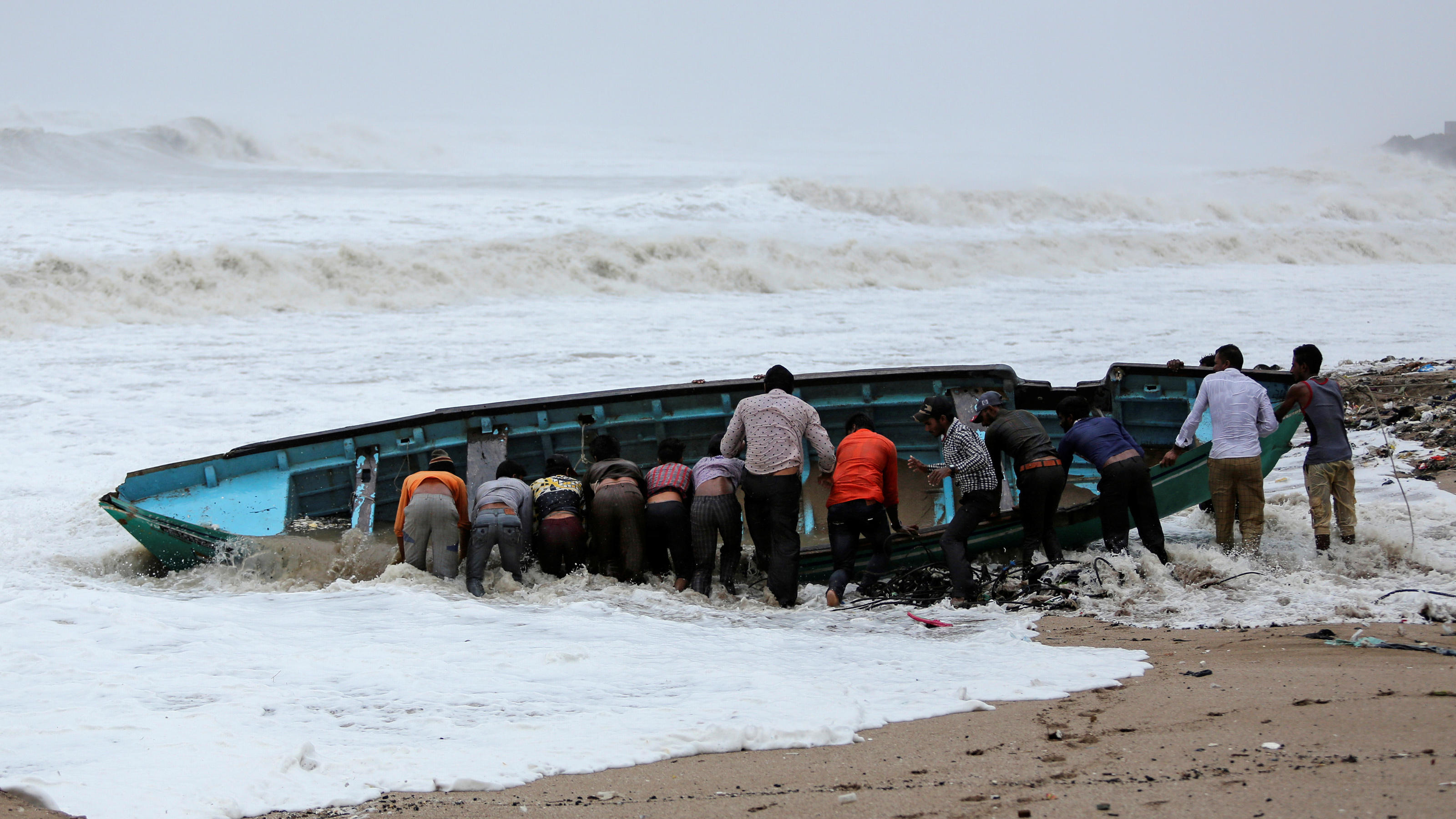 Fishermen move a fishing boat to a safer place along the shore ahead of Cyclone Vayu in Veraval, India, June 13, 2019. REUTERS/Amit Dave