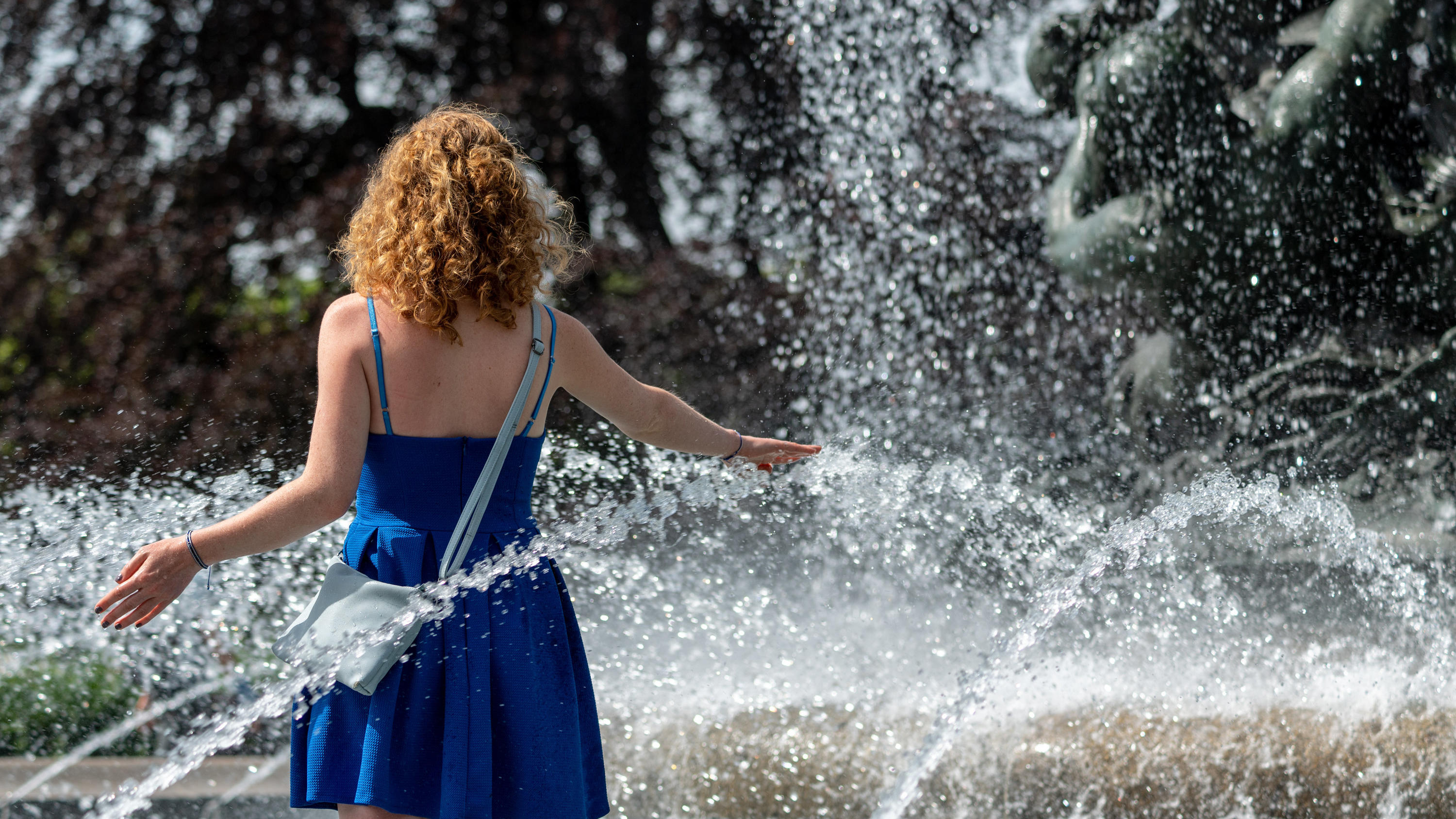 15.06.2019, Sachsen, Dresden: Nina aus Dresden läuft durch einen Brunnen am Albertplatz um sich abzukühlen. Foto: Robert Michael/dpa-Zentralbild/dpa +++ dpa-Bildfunk +++
