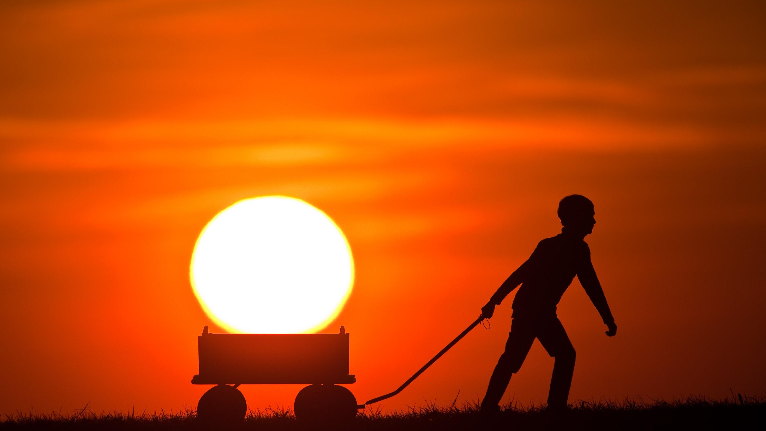 ARCHIV - Ein Junge zieht am 20.04.2009 einen Bollerwagen im Sonnenuntergang über ein Feld unweit dem brandenburgischen Alt Madlitz (Oder-Spree) und es scheint als würde er die Sonne in seinem Gefährt mitnehmen. Mit dem astronomischen (kalendarischen)