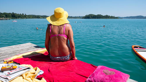 24.07.2019, Bayern, Inning: Eine Frau sitzt mit Sonnenhut und Bikini in der heißen Sonne auf einem Steg am Wörthsee. Foto: Sven Hoppe/dpa +++ dpa-Bildfunk +++