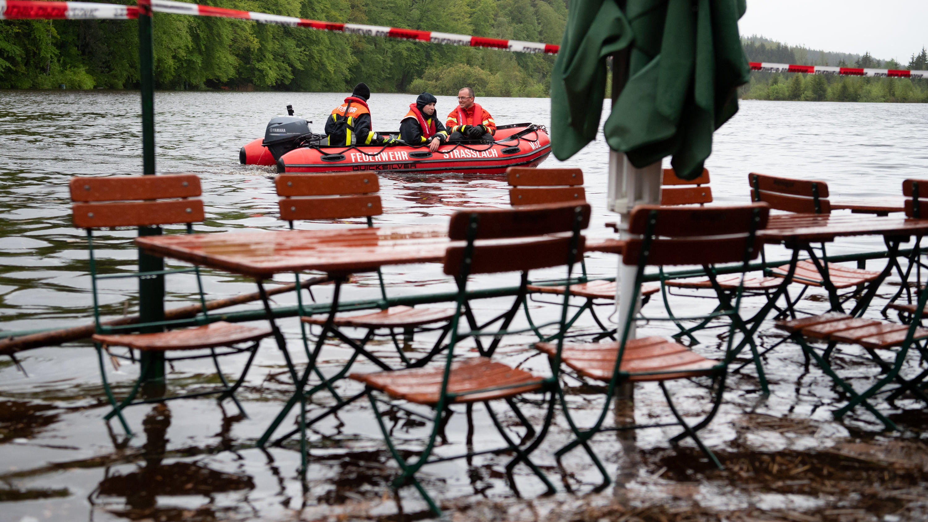 ARCHIV - 21.05.2019, Bayern, Straßlach: Feuerwehrmänner fahren mit einem Boot über den Deininger Weiher, der durch den starken Regen einen hohen Wasserstand hat und bereits einen Biergarten überflutet hat. (zu dpa «Studie: Klimawandel verschärft Hoch