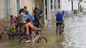 14.09.2019, Spanien, El Raal: Menschen fahren nach heftigen Regenfällen Fahrrad auf einer überfluteten Straße. Die Mittelmeerküste Spaniens ist von den schwersten Herbstunwettern der vergangenen drei Jahrzehnte getroffen worden. Die Leiche des sechsten Todesopfers, eines 41 Jahre alten Mannes, sei am Samstag (14.09.2019) in einem ländlichen Gebiet der Gemeinde Orihuela gefunden worden. Foto: Alfonso Duran/AP/dpa +++ dpa-Bildfunk +++