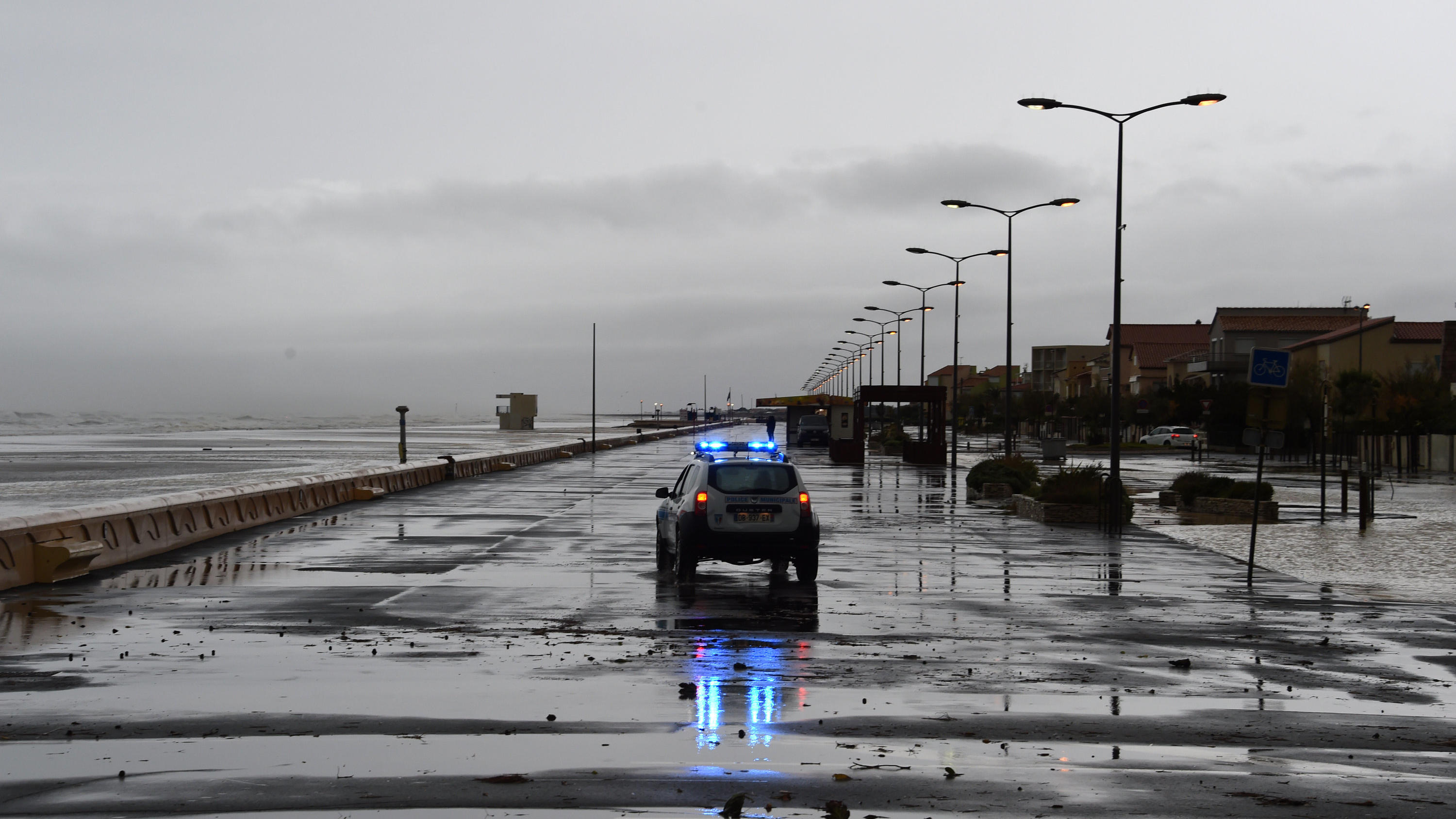 23.10.2019, Frankreich, Narbonne: Ein Polizeifahrzeug fährt nach den nächtlichen Stürmen vom 23. Oktober 2019 entlang der Strandpromenade von Narbonne in Südfrankreich. Die Departements Bouches-du-Rhone, Var und Vaucluse wurden nach nächtlichen Übers