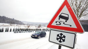 Ein Auto fährt am 09.01.2009 durch das Alte Feld in Arnsberg/Sauerland bei Schnee an einem Schild vorbei, das vor Glatteis und Schnee warnt. Foto: Fabian Stratenschulte