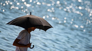 30.06.2019, Niedersachsen, Göttingen: Ein Mann schützt sich am Kiessee mit einem Regenschirm vor der Sonne. Am letzten Juni-Sonntag wird es noch einmal richtig heiß. Der Deutsche-Wetterdienst (DWD) rechnet mit Temperaturen bis 39 Grad. Foto: Swen Pförtner/dpa +++ dpa-Bildfunk +++