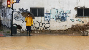 31.03.2020, Spanien, Malaga: Ein Mann mit Mundschutz steht vor einer überfluteten Kreuzung in Malaga, Südspanien. Foto: Álex Zea/Europa Press/dpa +++ dpa-Bildfunk +++