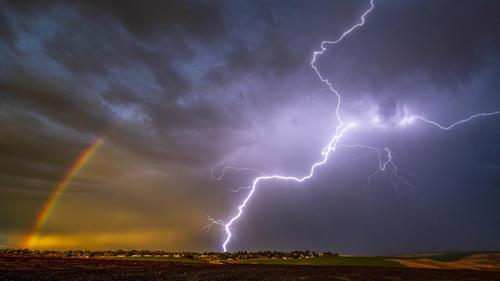 29.04.2020, USA, Lewiston: Ein Blitz schlägt in der Nähe eines Regenbogens ein, während es stark gewittert. Foto: Pete Caster/Lewiston Tribune/AP/dpa +++ dpa-Bildfunk +++