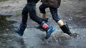 29.04.2020, Berlin: Kinder rennen im Bezirk Köpenick mit Gummistiefeln durch große Regenpfützen, die sich nach heftigen Regenschauern auf den Straßen gebildet haben. Nach wochenlanger Dürre ging am Nachmittag in der Hauptstadt der lang ersehnte Regen nieder. Nach Angaben der Meteorologen wird auch in den kommenden Tagen mit Regenfällen bei sinkenden Temperaturen zu rechnen sein. Foto: Wolfgang Kumm/dpa +++ dpa-Bildfunk +++
