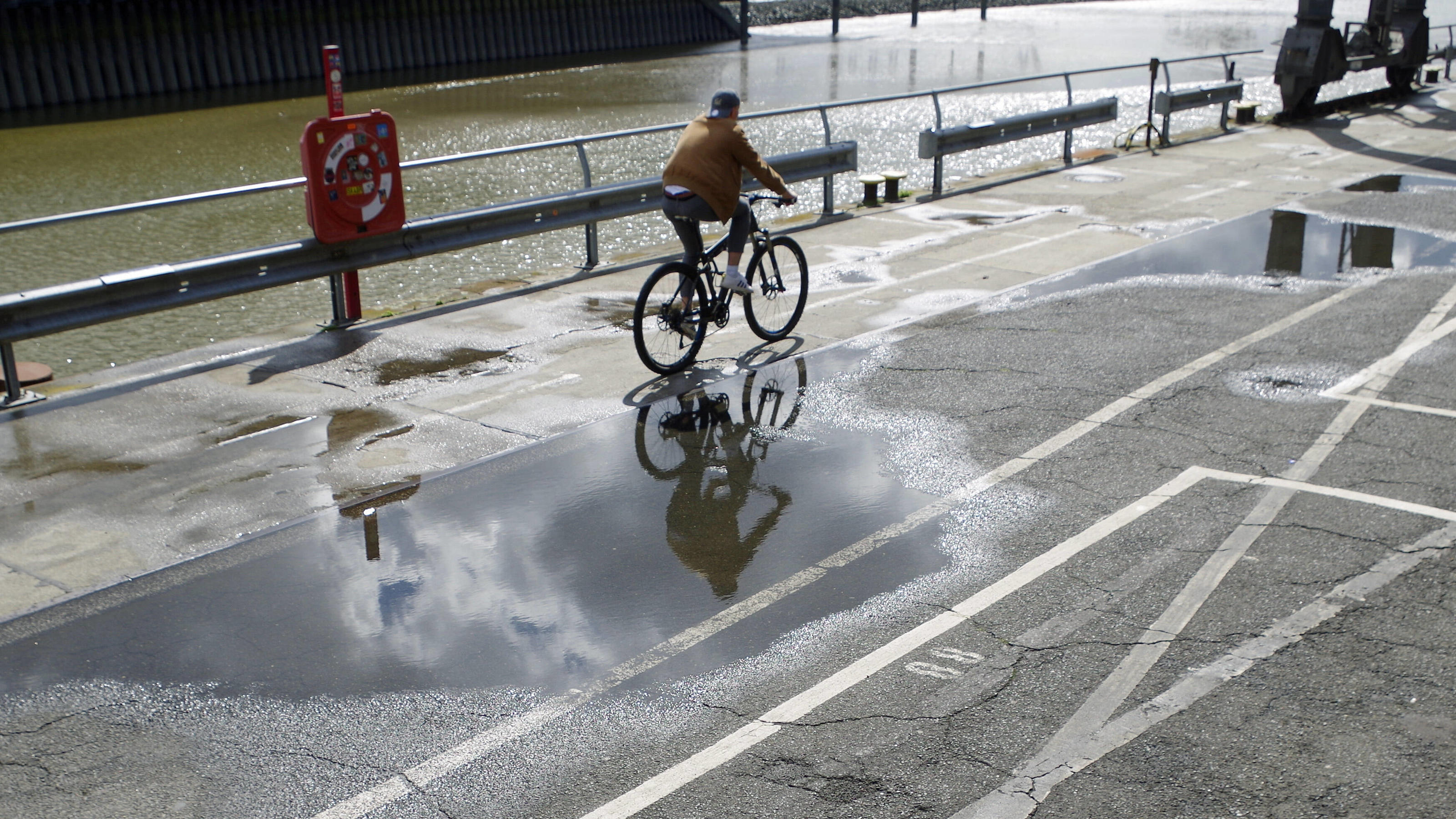  Feature: Wechselhaftes Wetter in Hamburg im Juli 2020. Ein Radfahrer spiegelt sich in einer Pfütze. *** Feature Changeable weather in Hamburg in July 2020 A cyclist is reflected in a puddle