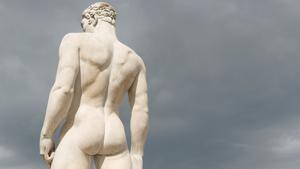Statue of a muscular male athlete warms his buns against moody gray sky