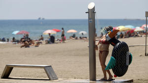 15.07.2020, Spanien, Malaga: Eine Besucherin mit Mundschutz duscht an einem Strand in Malaga. Sowohl in Andalusien als auch in sieben anderen Regionen Spaniens ist das Tragen einer Maske vorgeschrieben, selbst wenn der Sicherheitsabstand eingehalten werden kann. In Andalusien ist das Tragen einer Mundschutzmaske am Strand ebenfalls Pflicht. Foto: Álex Zea/EUROPA PRESS/dpa +++ dpa-Bildfunk +++