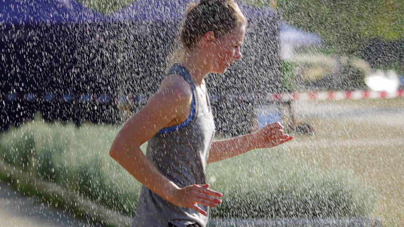 Feature bei extremer Hitze: Eine Teilnehmerin am Inselparklauf in Hamburg-Wilhelmsburg erfrischt sich während des Laufes unter einer bereitgestellten Dusche. *** Feature Sport in extreme heat A participant in the Inselparklauf in Hamburg Wilhelmsbur