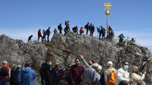 People queue to reach the summit cross on top of the highest German mountain 'Zugspitze' (2962 meters) near Garmisch-Partenkirchen, Germany, Wednesday, Aug.19, 2020. (AP Photo/Matthias Schrader)
