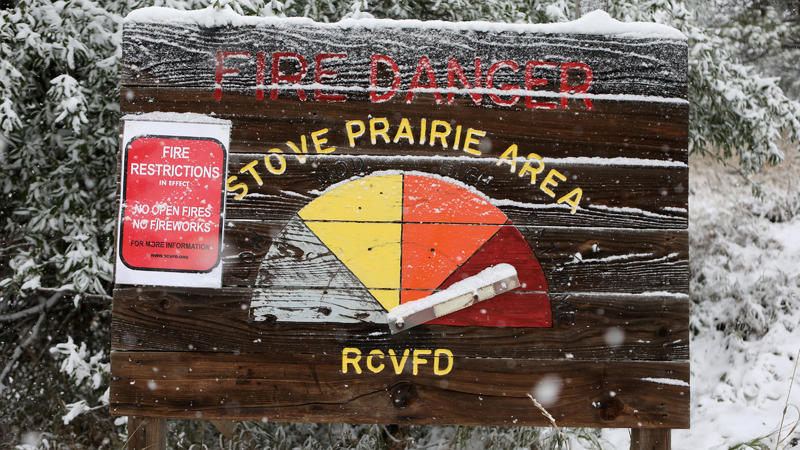 A warning sign lists the fire danger as extreme near a Colorado National Guard staffed roadblock leading to the Cameron Peak wildfire as snow falls a day after the region sweltered through temperatures in the 90s Fahrenheit (32 degrees Celsius) outsi