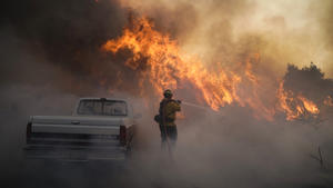 ARCHIV - 26.10.2020, USA, Irvine: Ein Feuerwehrmann ist beim Silverado Fire im Einsatz. Vier von fünf Naturkatastrophen sind nach einer Studie des Roten Kreuzes in den vergangenen zehn Jahren auf extremes Wetter und die Folgen der Klimakrise zurückgegangen. Dazu gehören Unwetter, Überschwemmungen und Hitzewellen. (zu dpa: "Rotes Kreuz: Mehr Katastrophen durch Klimawandel und Extremwetter") Foto: Jae C. Hong/AP/dpa +++ dpa-Bildfunk +++