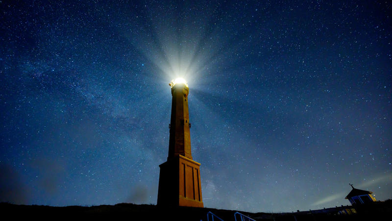 28.02.2020, Niedersachsen, Norderney: Bei klarem Himmel sind die Sterne über Norderney zu sehen, während das Licht des Leuchtturms der Insel hell strahlt. Foto: Mohssen Assanimoghaddam/dpa +++ dpa-Bildfunk +++